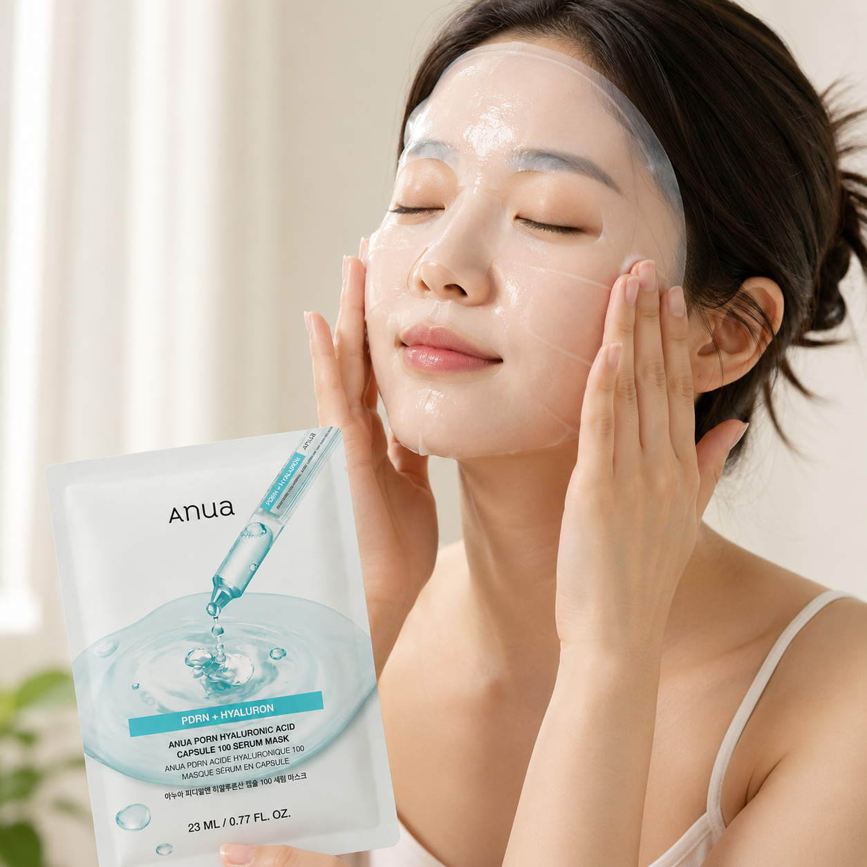 Mujer aplicando una mascarilla facial de tela mientras sostiene el empaque de Anua PDRN Hyaluronic Acid Capsule 100 Serum Mask.
