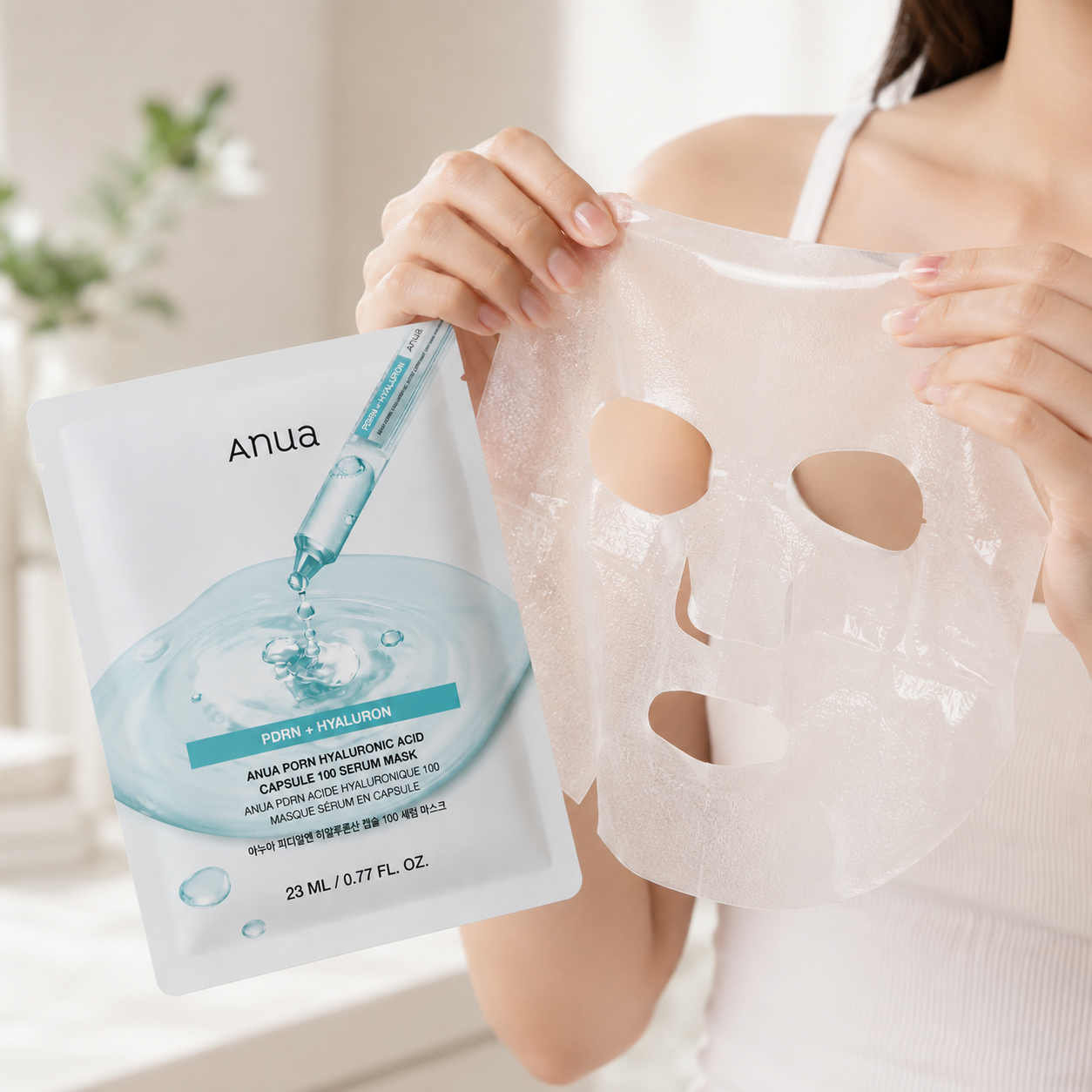 Mujer sosteniendo con ambas manos la mascarilla facial de tela impregnada en sérum de Anua PDRN Hyaluronic Acid, mostrando su textura hidratante junto al empaque del producto.